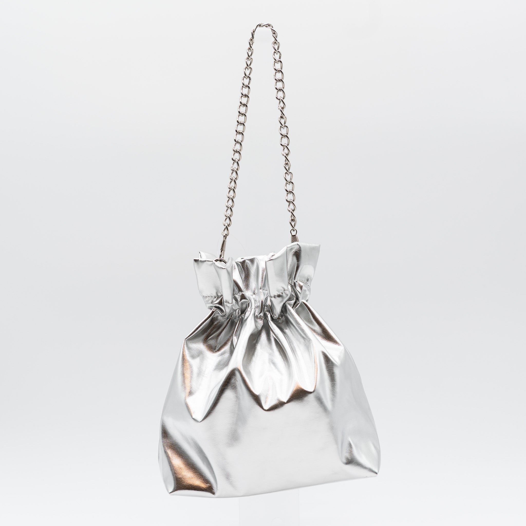Bolso bombonera de fiesta en polipiel plata con acabado metalizado, diseño fruncido y asa de cadena