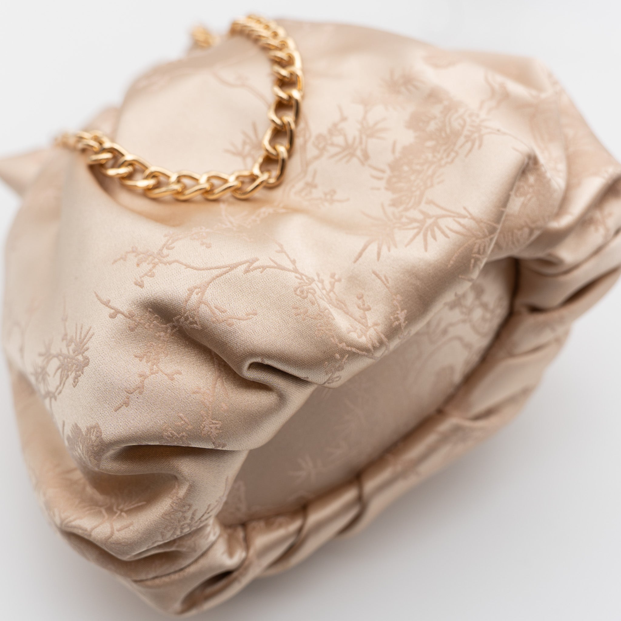 Bolso bombonera de fiesta en raso champan con bordado floral, cierre fruncido y asa de cadena