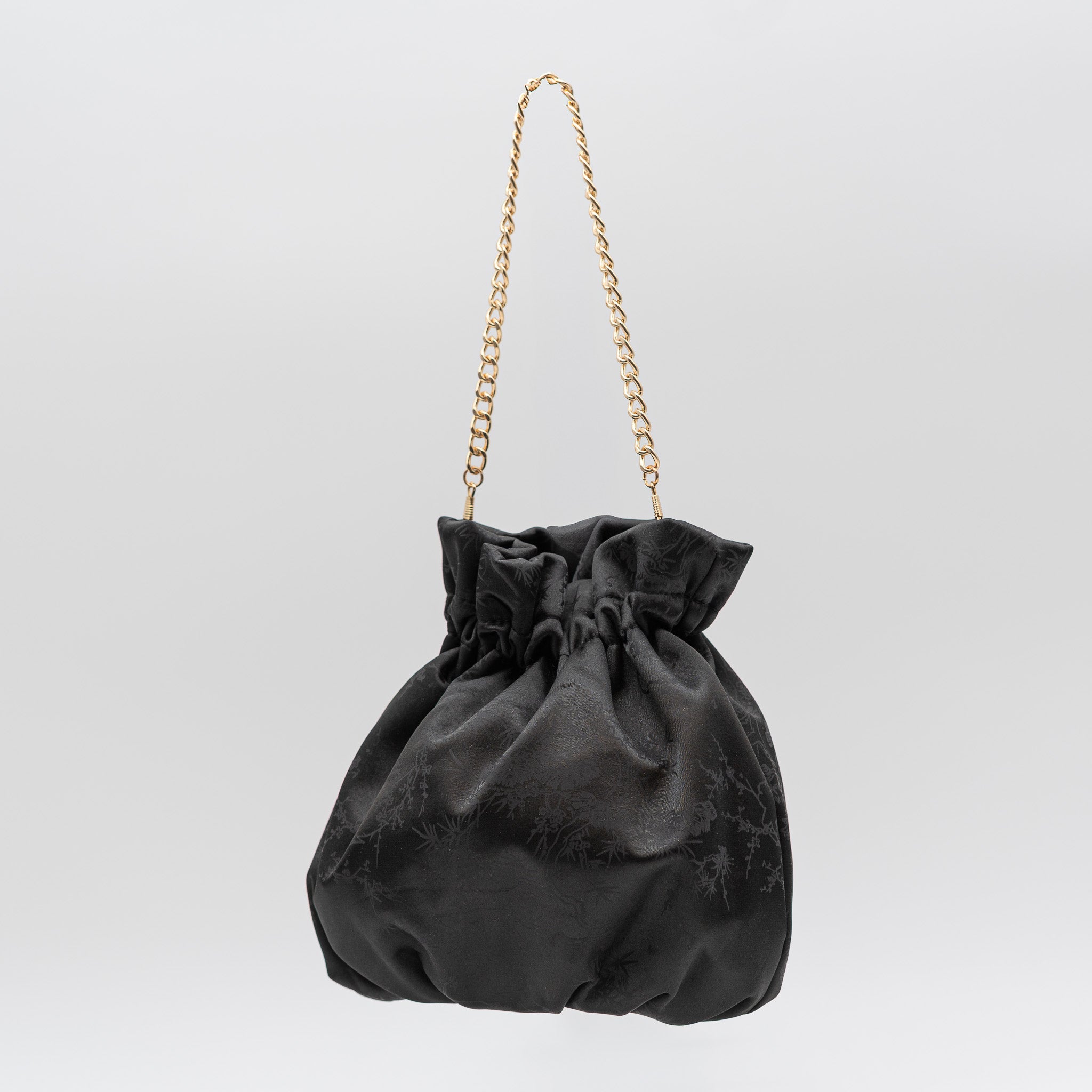 Bolso bombonera de fiesta en raso negro con bordado floral, cierre fruncido y asa de cadena