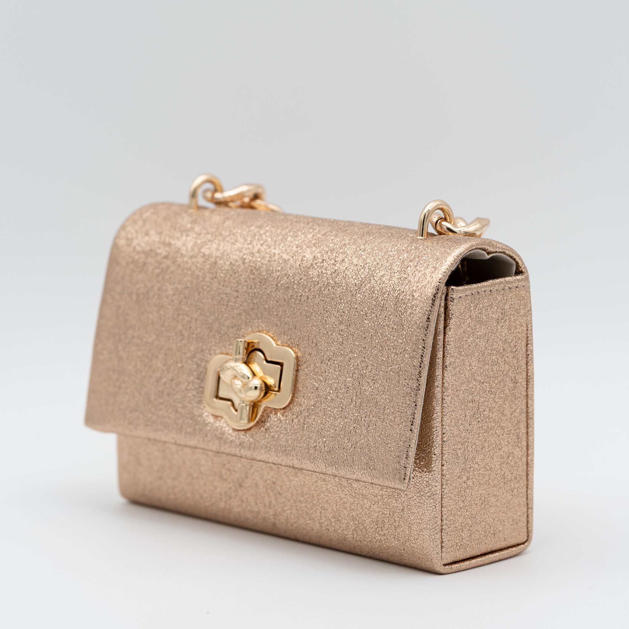 Bolso de fiesta en polipiel champán con acabado brillante, asa de cadena y cierre decorativo, ideal para bodas y cócteles