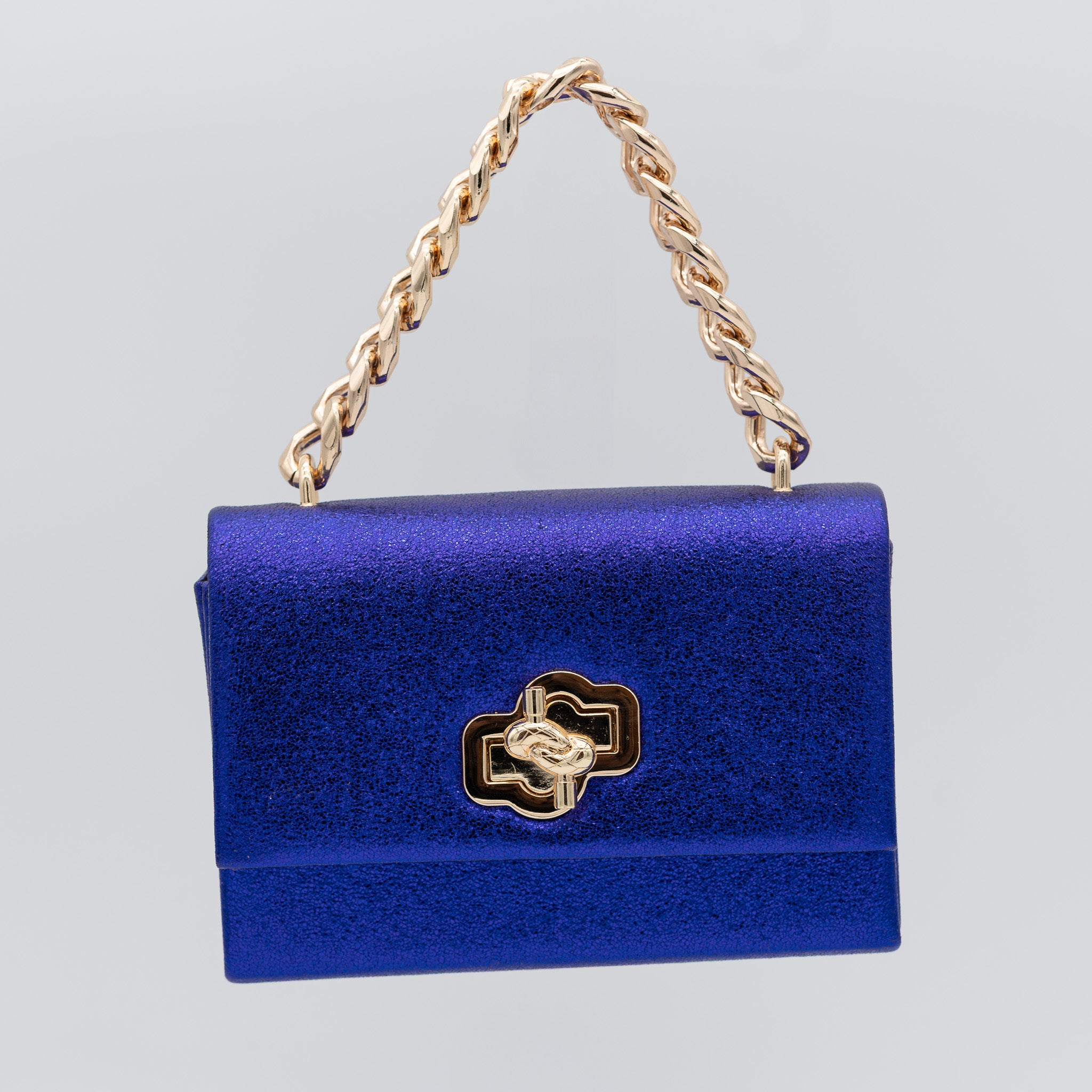 Bolso de fiesta en polipiel morado azul con acabado brillante, asa de cadena y cierre decorativo, ideal para bodas y cócteles