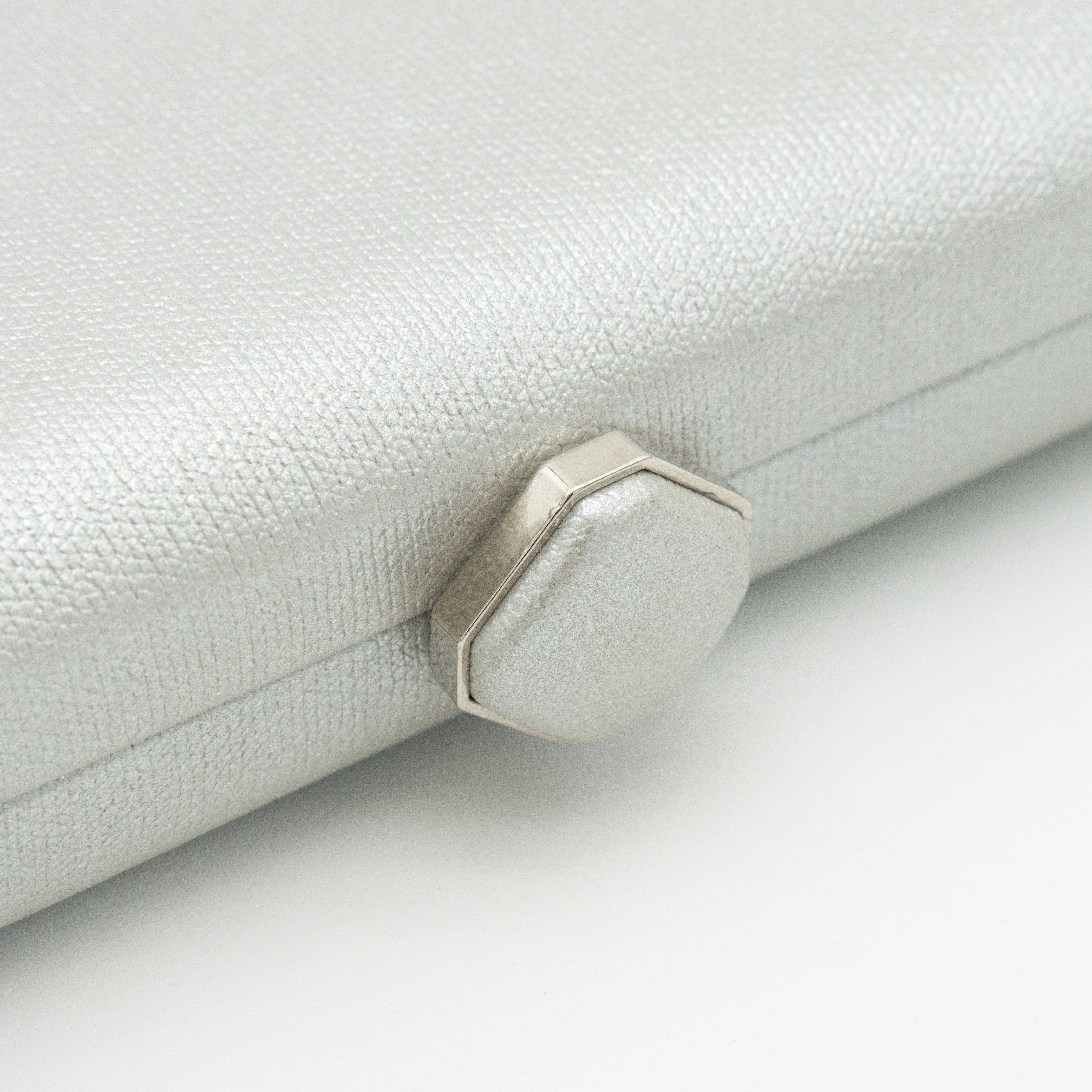 Bolso clutch de polipiel metalizado plata con cierre superior hexagonal y cadena desmontable