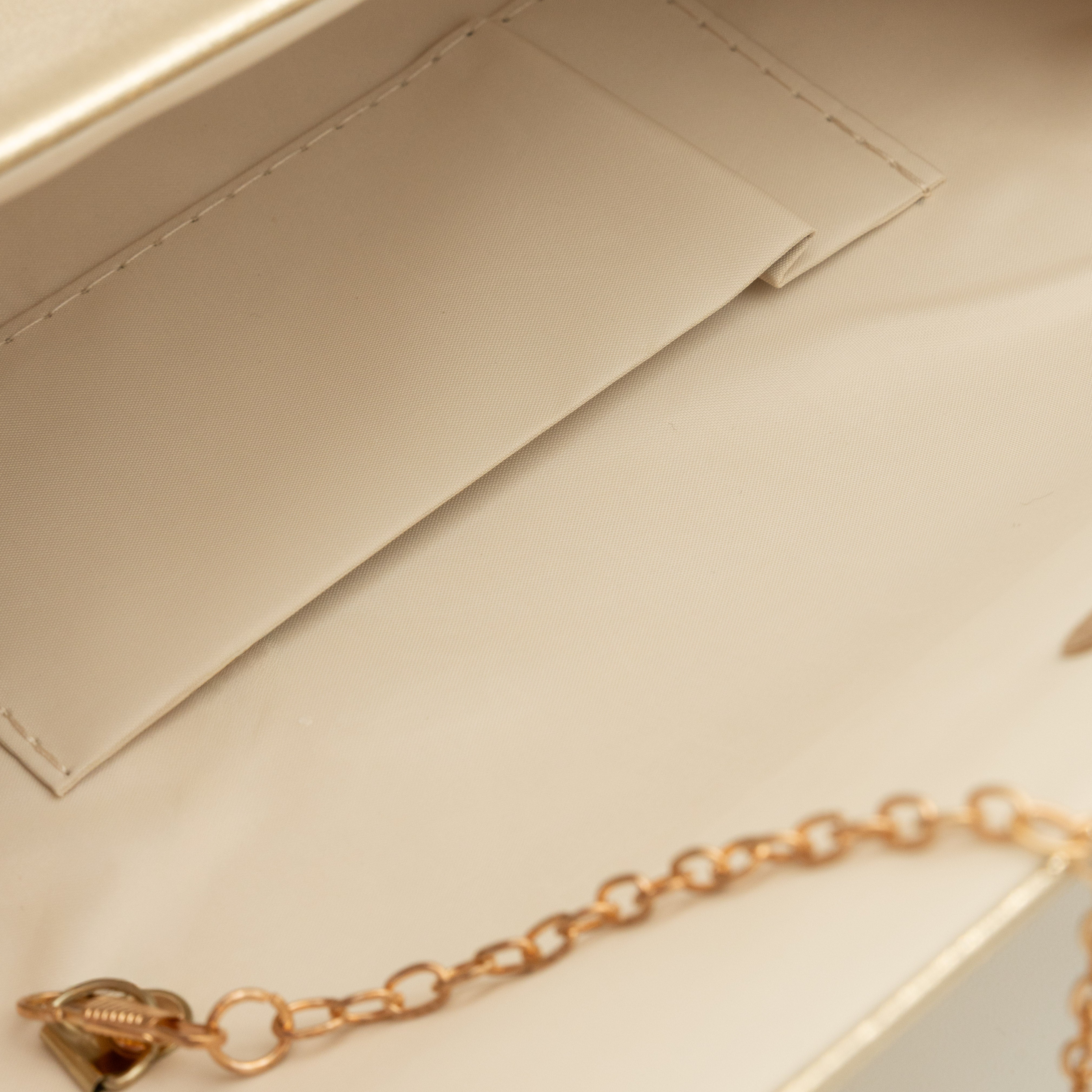 Bolso clutch de polipiel metalizado oro claro con solapa frontal y cadena metálica desmontable
