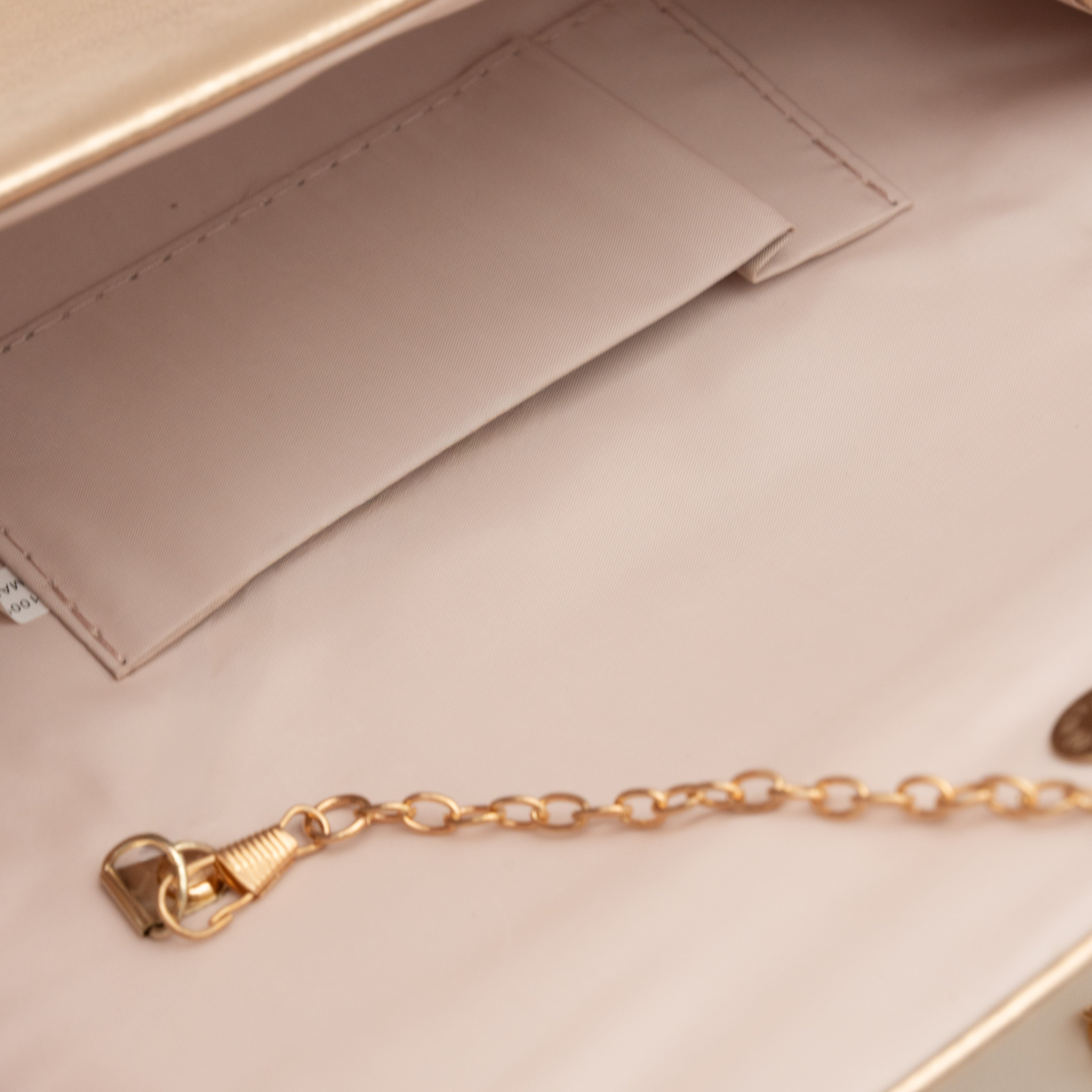 Bolso clutch de polipiel metalizado oro rosa con solapa frontal y cadena metálica desmontable