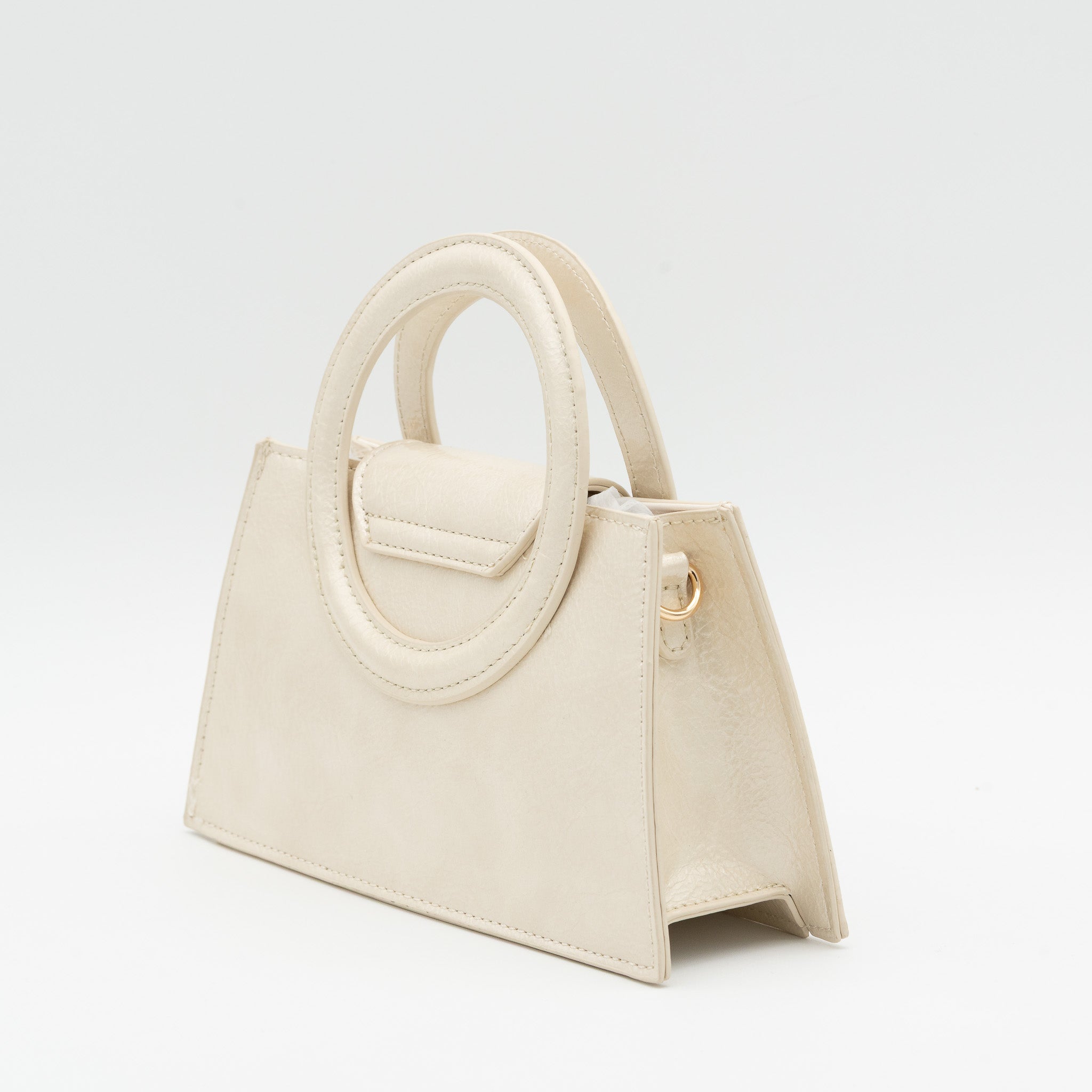 Bolso de mano beige acharolado con asa circular rígida y cadena dorada desmontable