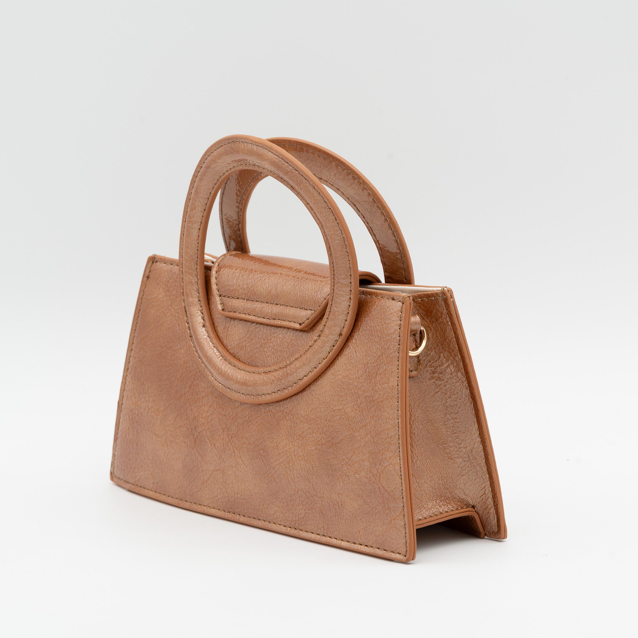 Bolso de mano cuero acharolado con asa circular rígida y cadena dorada desmontable