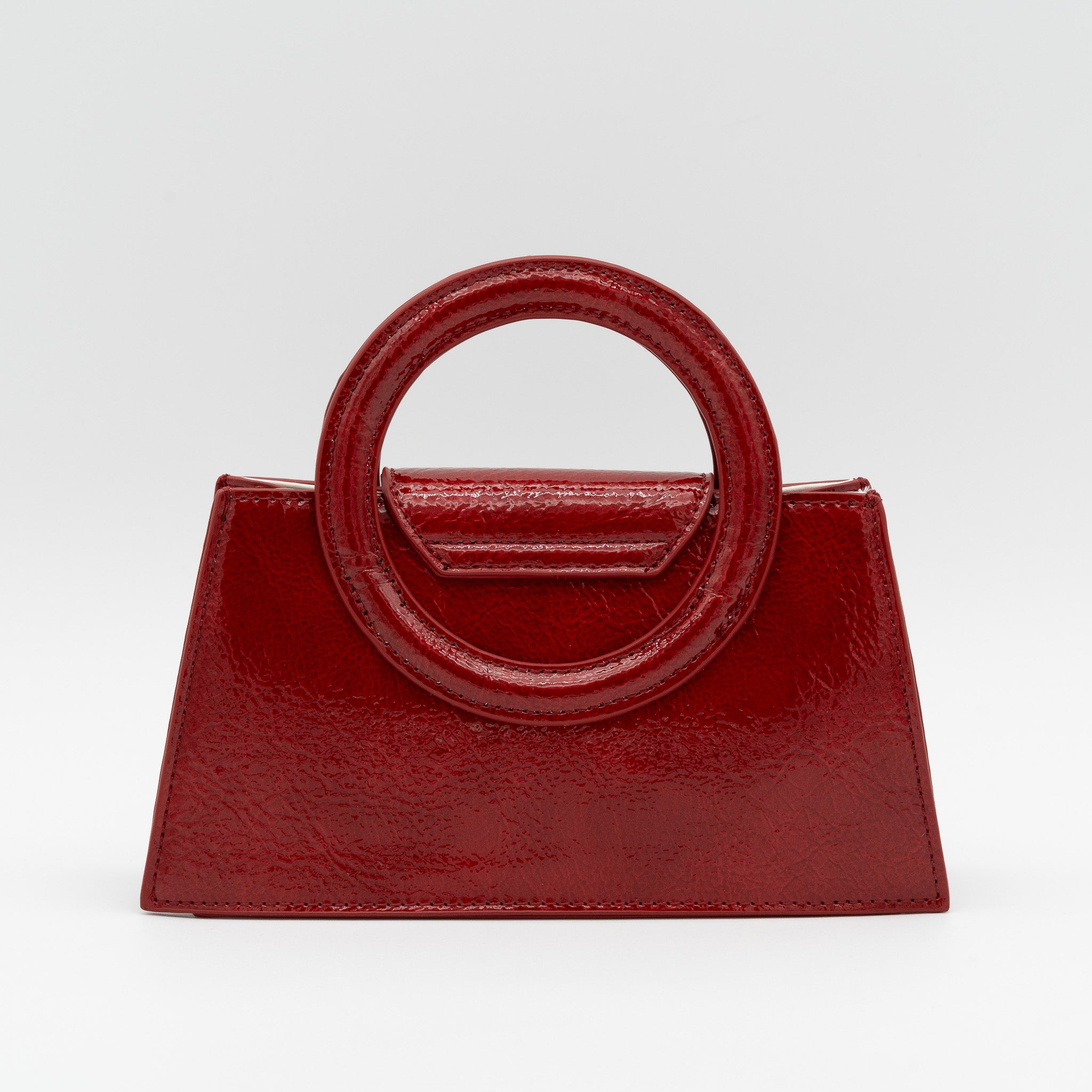 Bolso de mano rojo oscuro acharolado con asa circular rígida y cadena dorada desmontable