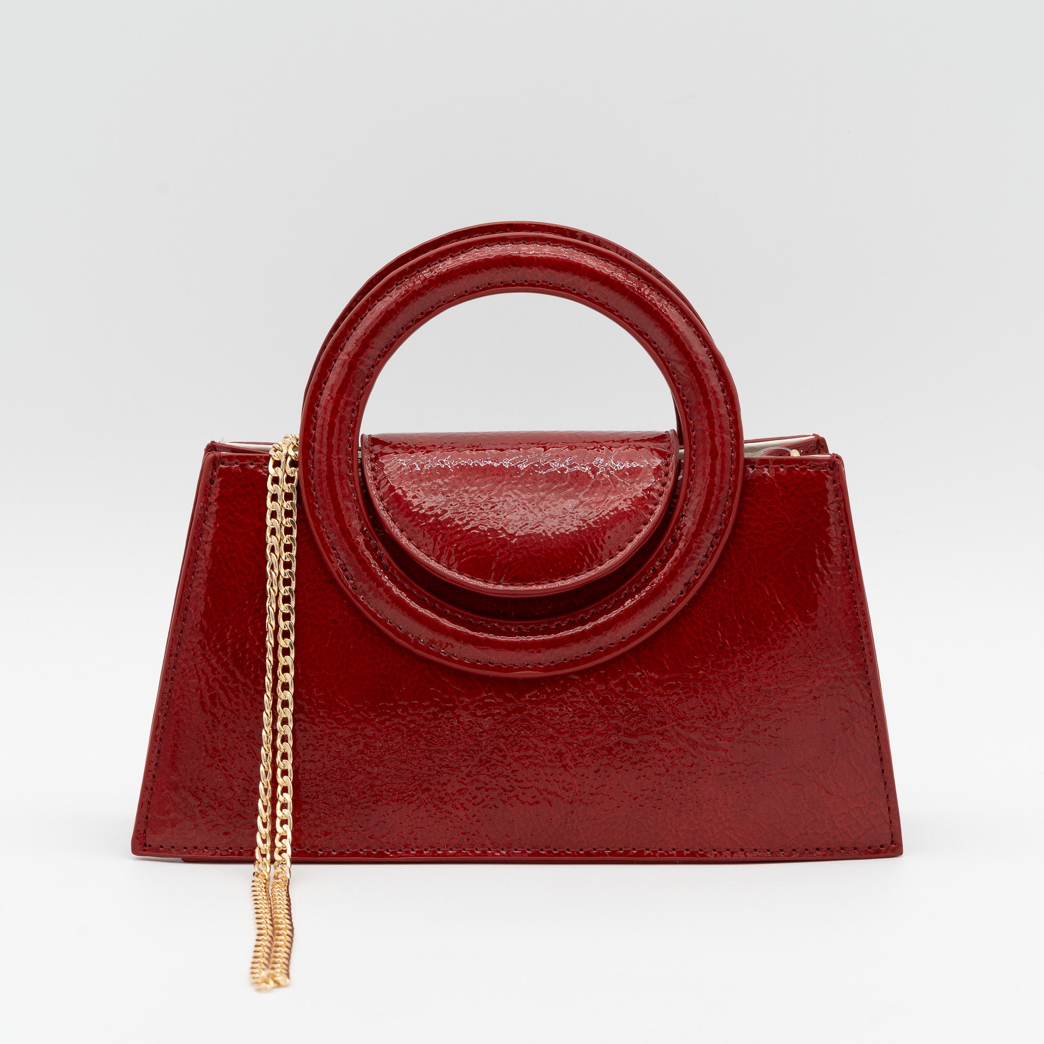 Bolso de mano rojo oscuro acharolado con asa circular rígida y cadena dorada desmontable