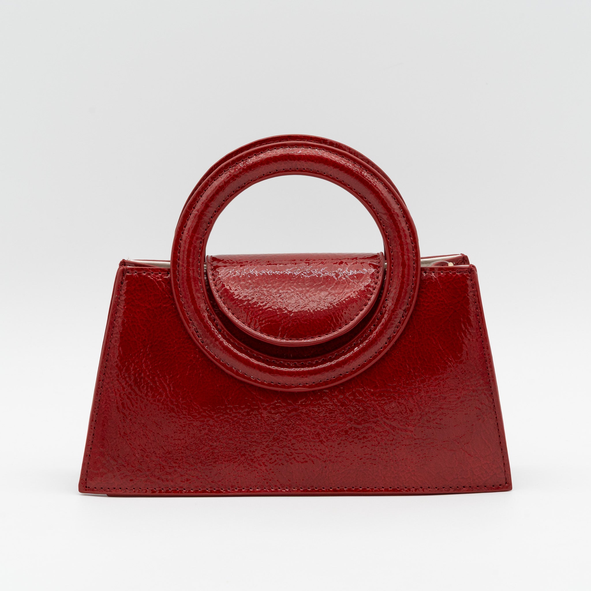Bolso de mano rojo oscuro acharolado con asa circular rígida y cadena dorada desmontable