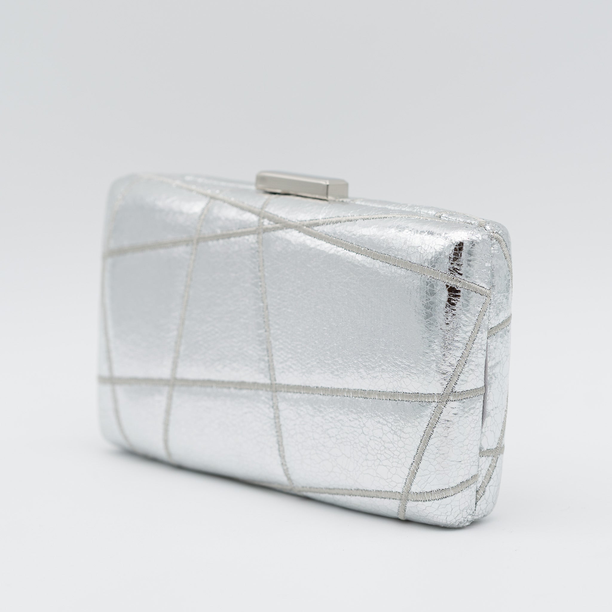 Clutch de fiesta en polipiel plata con bordado geométrico, efecto metalizado, cierre metálico y cadena desmontable, ideal para bodas y cócteles