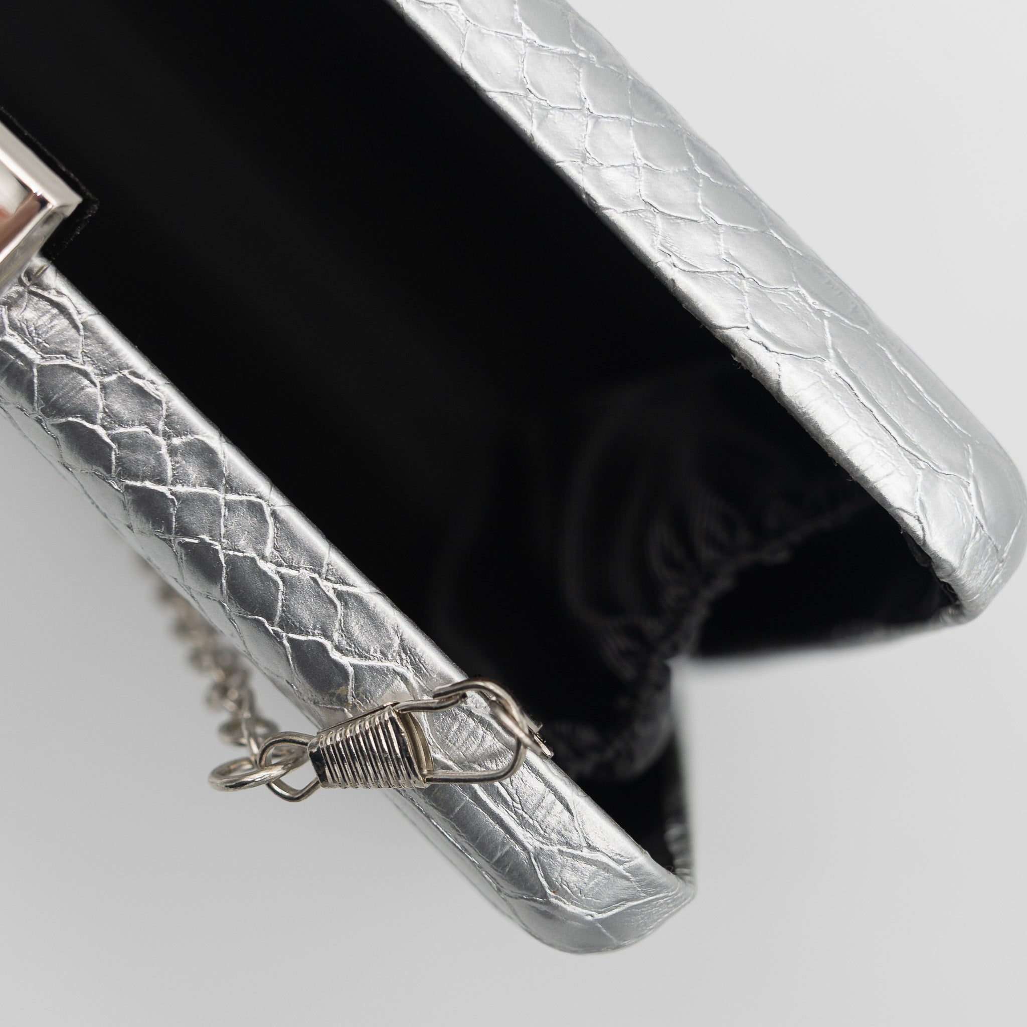Clutch de fiesta en polipiel con textura de reptil color plata, cierre metálico y cadena desmontable, ideal para bodas y cócteles