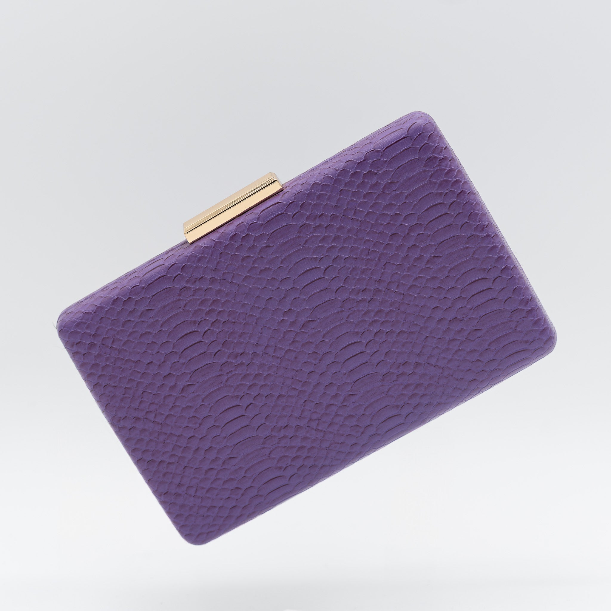 Clutch de fiesta en polipiel con textura de reptil color violeta, cierre metálico y cadena desmontable, ideal para bodas y cócteles