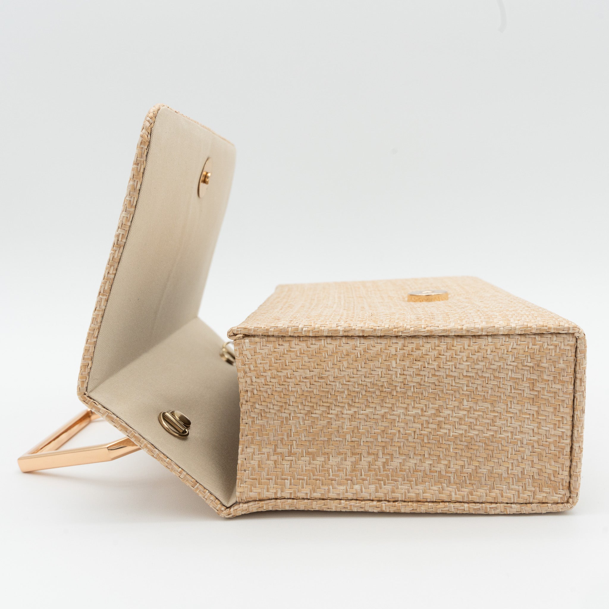 Clutch de fiesta en rafia beige con asa geométrica metálica y cierre magnético, perfecto para bodas y cócteles