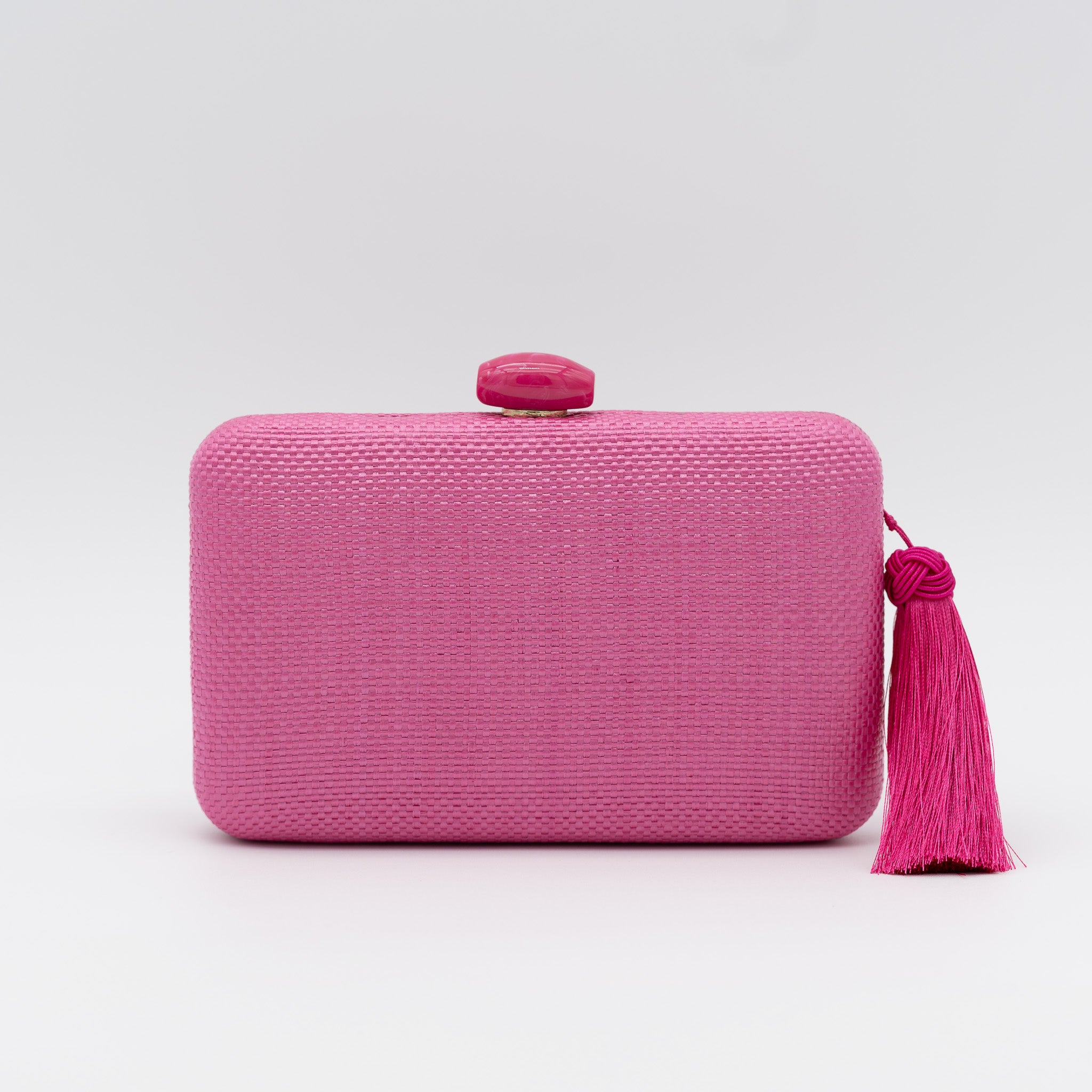 Bolso clutch de fiesta de rafia con broche ovalado en la parte superior y borla lateral en color fucsia