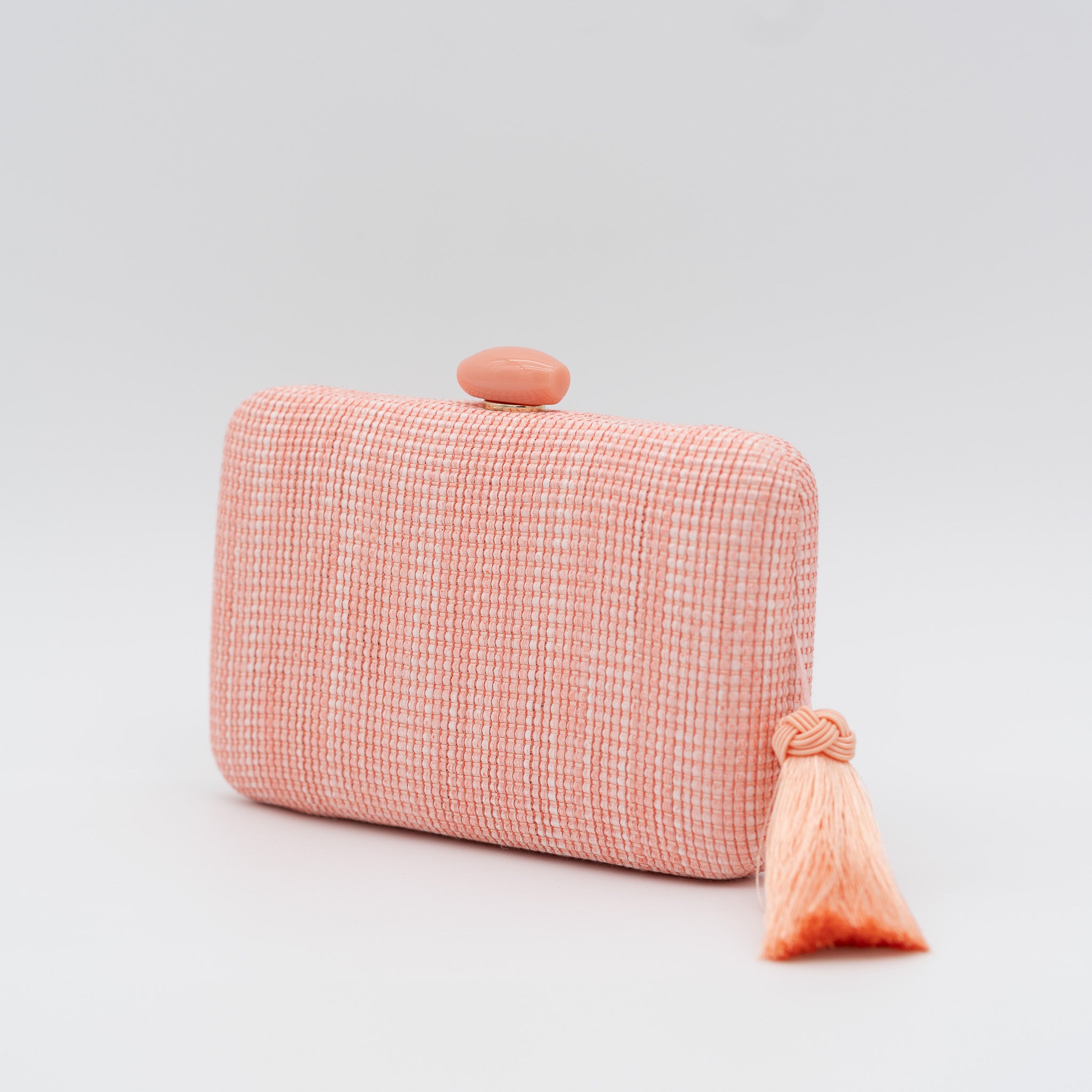 Bolso clutch de fiesta de rafia con broche ovalado en la parte superior y borla lateral en color melocotón