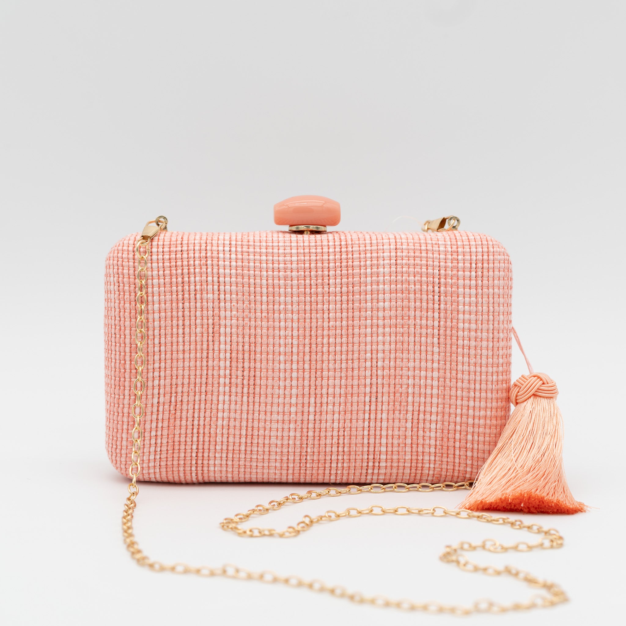 Bolso clutch de fiesta de rafia con broche ovalado en la parte superior y borla lateral en color melocotón