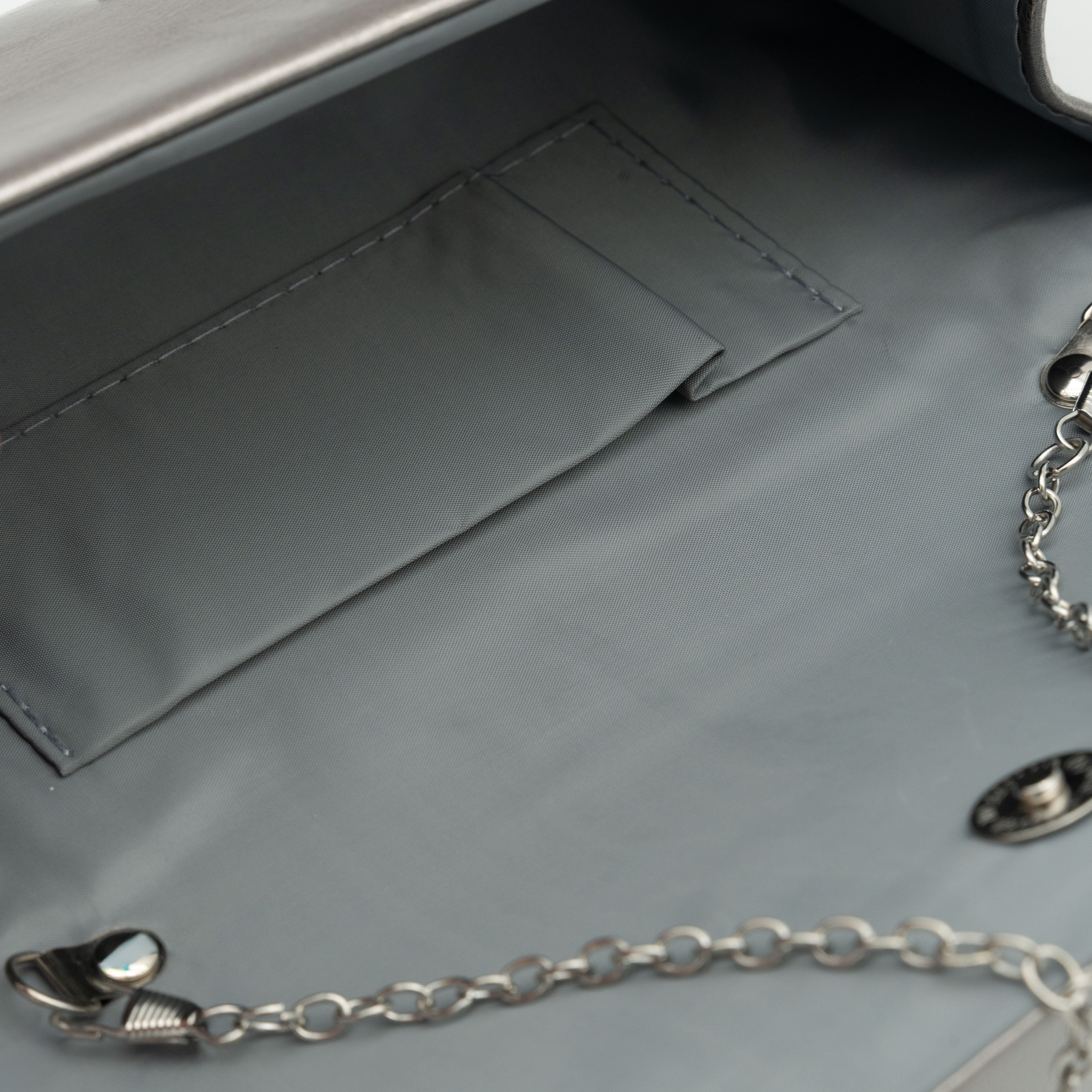 Bolso clutch de polipiel metalizado gris con solapa frontal y cadena metálica desmontable